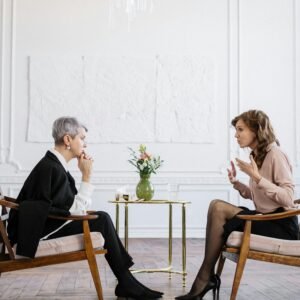 Oferta Two women engaged in a counseling session in a bright, modern loft setting.